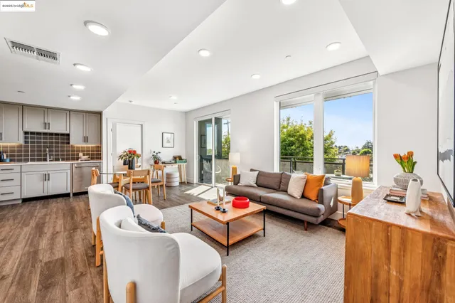 a living room with furniture kitchen view and a large window