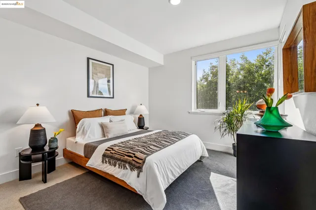 a bedroom with a bed a potted plant and a large window