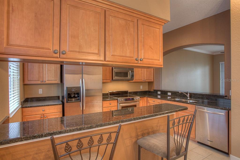 6021 Printery Street, Unit 106 Tampa, FL 33616 - Photo 7 of 23 a kitchen with stainless steel appliances granite countertop a stove a sink and a microwave