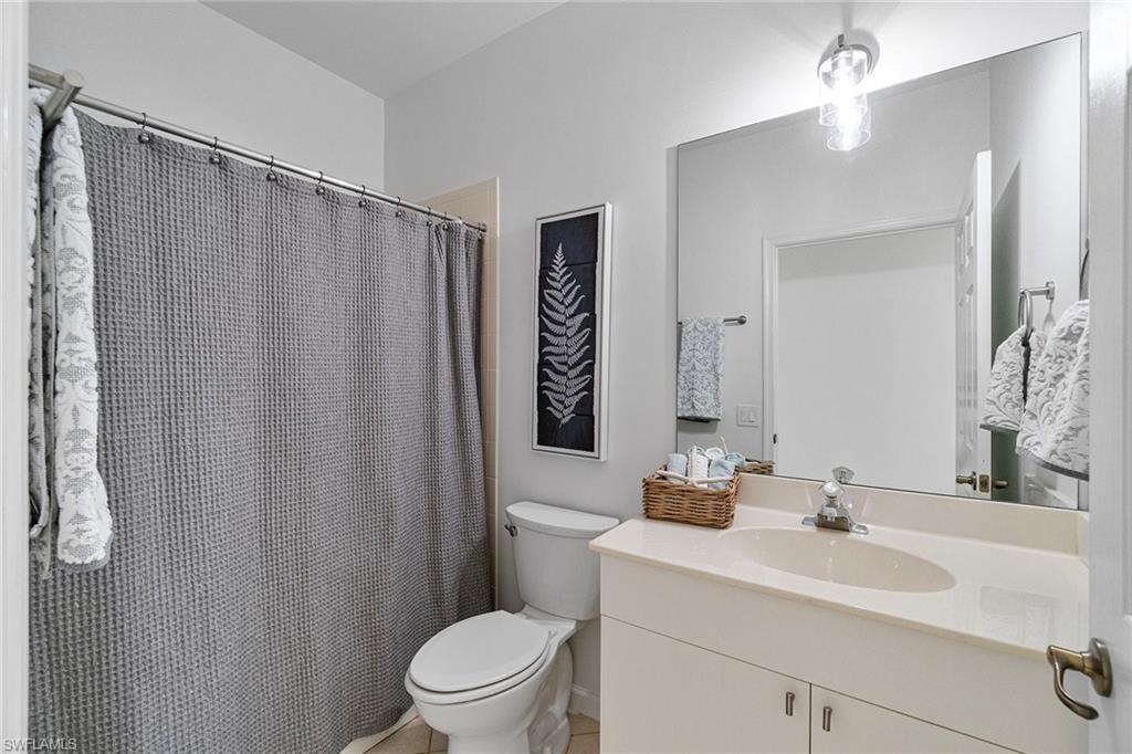 23081 Rosedale Drive, Unit 201 Estero, FL 34135 - Photo 12 of 18 a bathroom with a sink a toilet a mirror and shower curtain