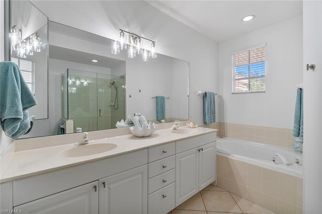23081 Rosedale Drive, Unit 201 Estero, FL 34135 - Photo 9 of 18 a bathroom with a granite countertop sink a large mirror a bathtub and shower