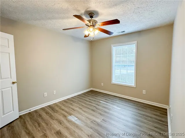 an empty room with window and ceiling fan