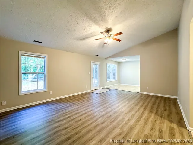 a view of an empty room with a window and wooden floor