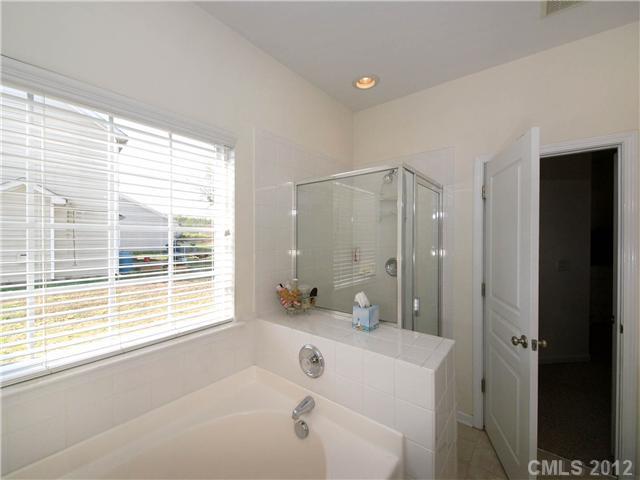 150 Whitley Mills Road Fort Mill, SC 29708 - Photo 8 of 16 a bathroom with a bathtub a shower a sink and a large mirror next to a window