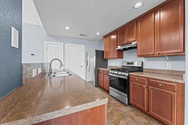 a kitchen with stainless steel appliances granite countertop a sink a stove and a refrigerator