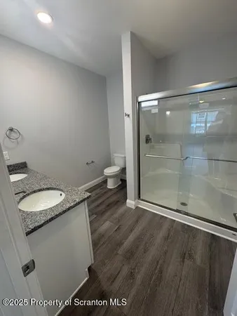 a bathroom with a granite countertop sink a toilet and shower
