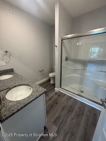 a bathroom with a granite countertop sink a toilet a mirror and shower