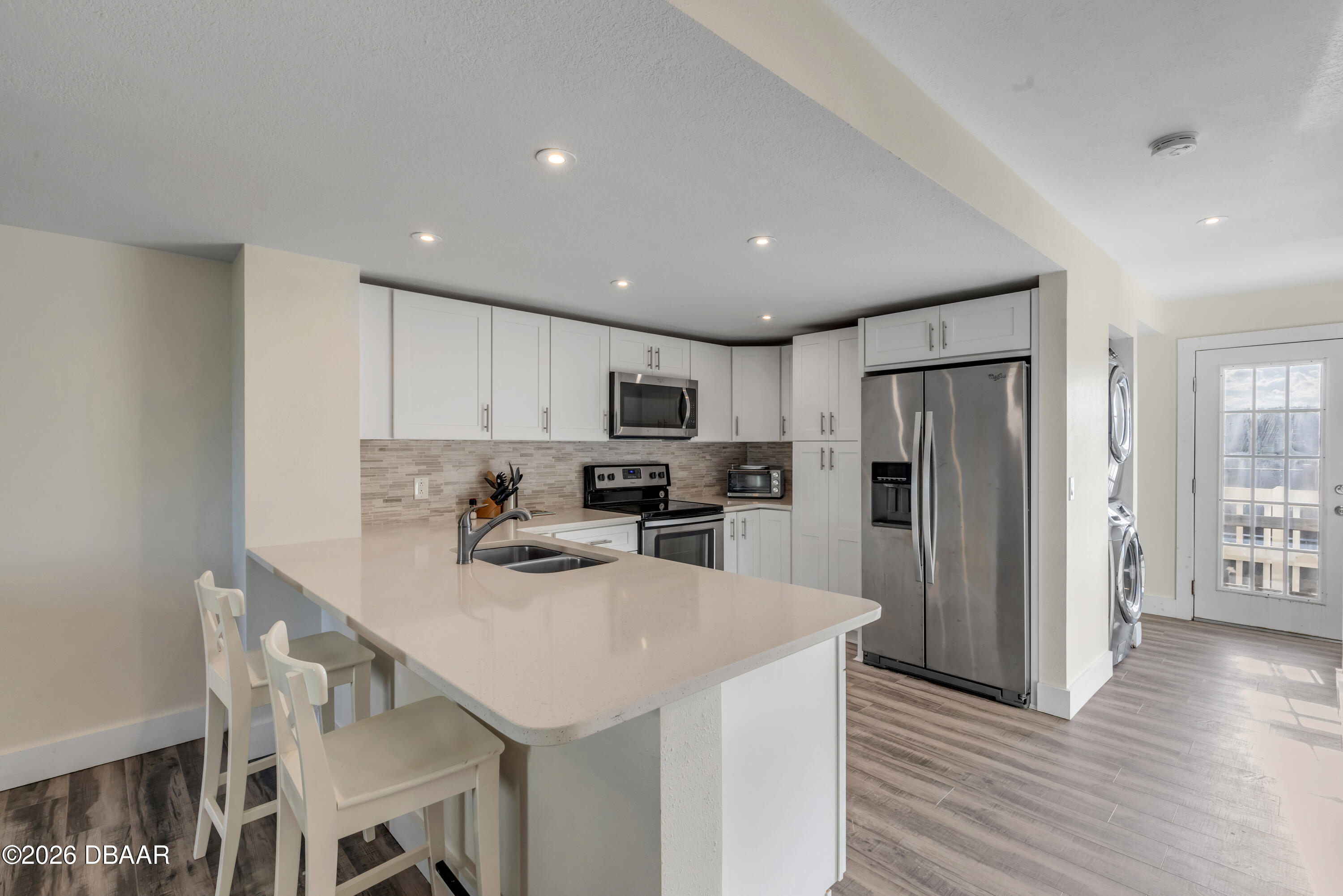 4752 South Atlantic Avenue, Unit 1 Ponce Inlet, FL 32127 - Photo 10 of 49 a kitchen with stainless steel appliances granite countertop a refrigerator a sink dishwasher a stove with wooden cabinets and wooden floor