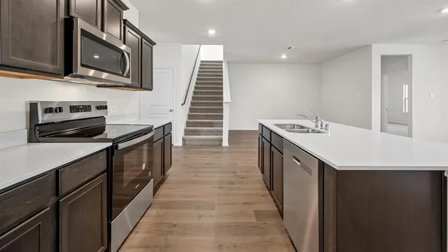 a kitchen with a sink appliances and wooden floor