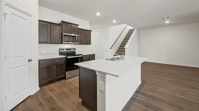 a kitchen with a sink a stove and wooden floor