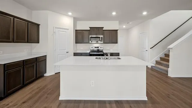 a kitchen with wooden floor and steel appliances