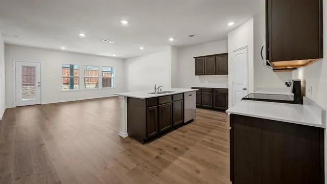 a view of kitchen with kitchen island granite countertop stainless steel appliances refrigerator sink and cabinets