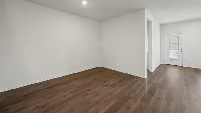 a view of an empty room with wooden floor and stairs
