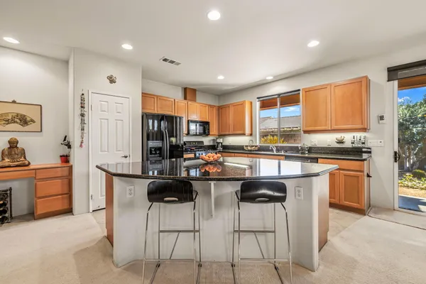 a kitchen with stainless steel appliances kitchen island granite countertop a stove a sink a refrigerator and a dining table