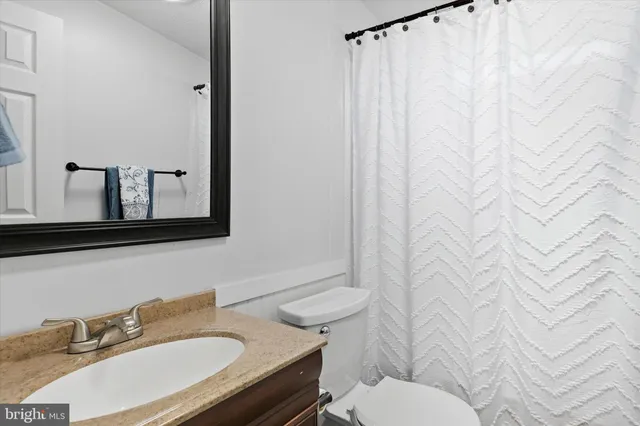 a bathroom with a granite countertop sink mirror and a toilet