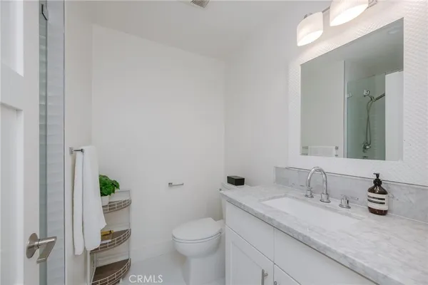 a bathroom with a granite countertop sink a toilet and a mirror
