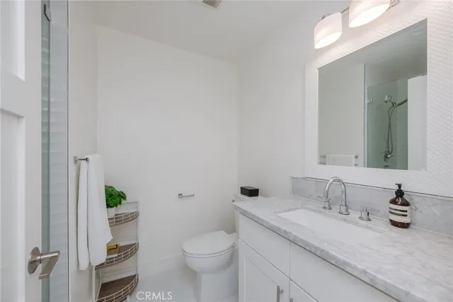 a bathroom with a granite countertop sink a toilet and a mirror