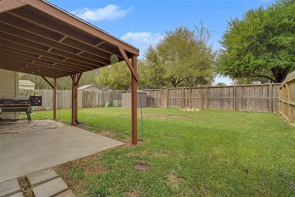 a view of a backyard with wooden fence and a large tree