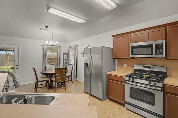 a kitchen with stainless steel appliances granite countertop a stove top oven a sink a dining table and chairs