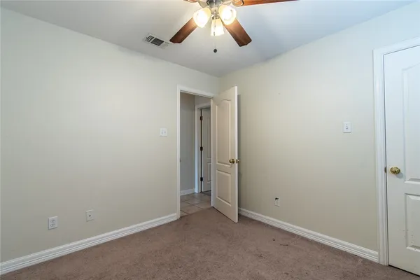 an empty room with a ceiling fan and carpet