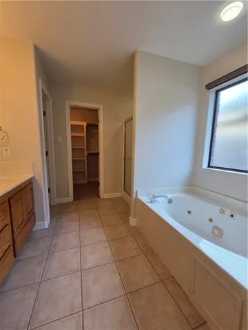 an empty room with a chandelier fan and windows