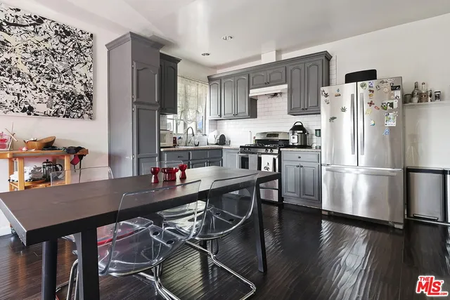 a kitchen with stainless steel appliances a dining table chairs stove refrigerator and cabinets