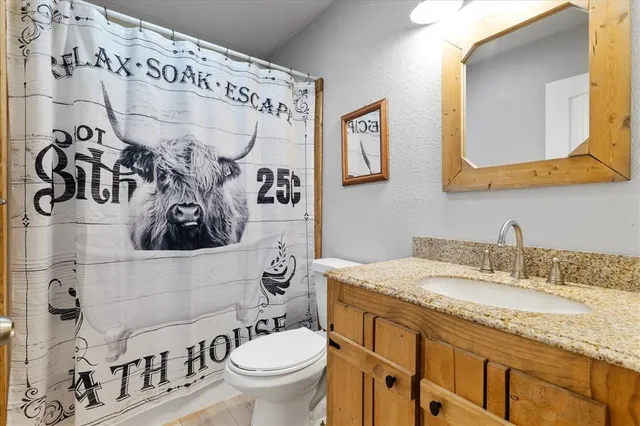 a bathroom with a granite countertop sink mirror vanity and toilet