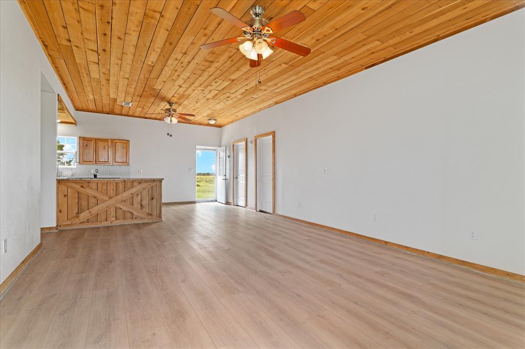 3300 Airport Road Tioga, TX 76271 - Photo 7 of 37 a view of an empty room with wooden floor and a ceiling fan