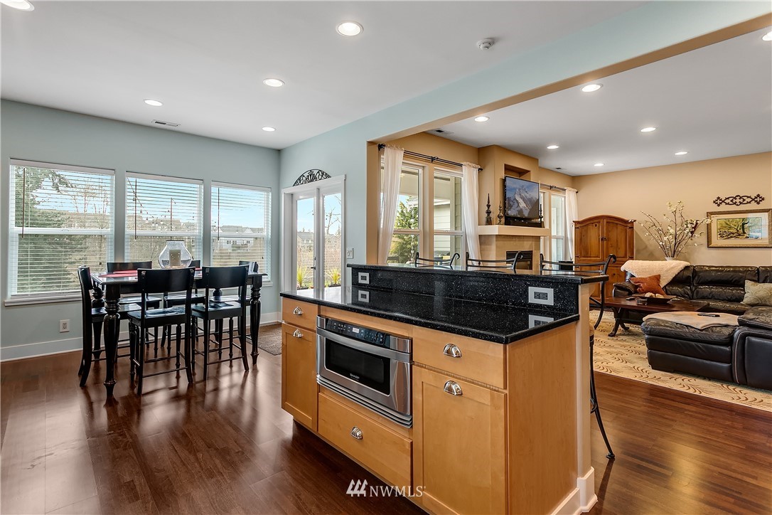 5615 Northeast 10th Street Renton, WA 98059 - Photo 9 of 35 a kitchen with stainless steel appliances granite countertop a stove top oven a sink a dining table and chairs with wooden floor
