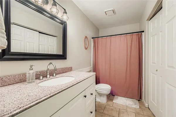a bathroom with a granite countertop sink mirror vanity and toilet