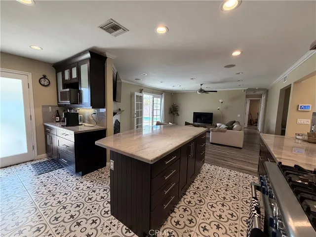 a large kitchen with stainless steel appliances kitchen island granite countertop a large stove a sink dishwasher and cabinets with wooden floor