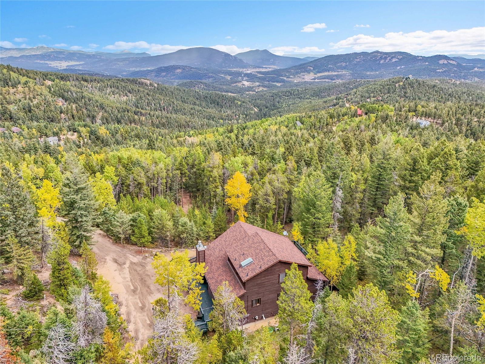 11333 Conifer Mountain Road Conifer, CO 80433 - Photo 2 of 50 a view of a lush green hillside and a houses