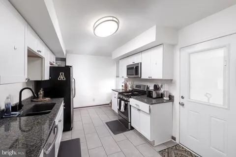 a kitchen with granite countertop a sink stove and refrigerator