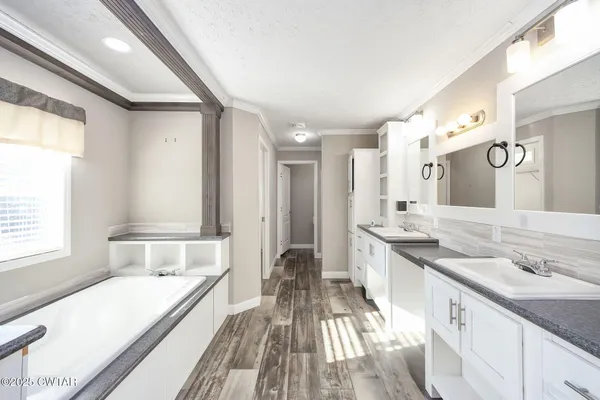 a spacious bathroom with a granite countertop sink a large mirror and a bathtub