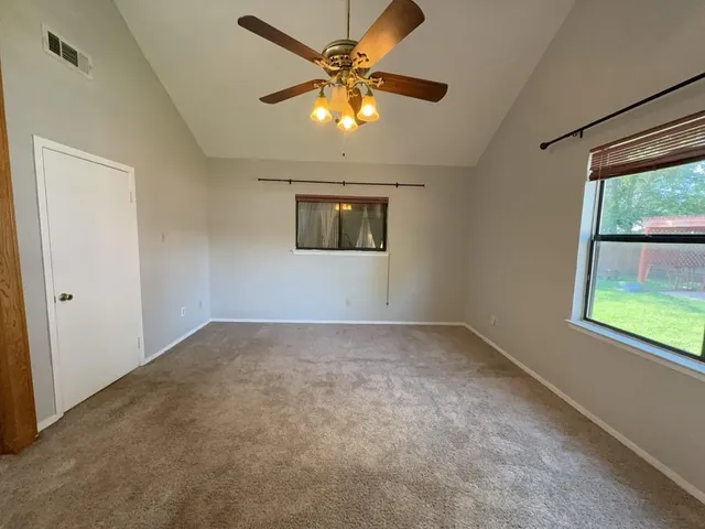 a view of an empty room with a chandelier fan
