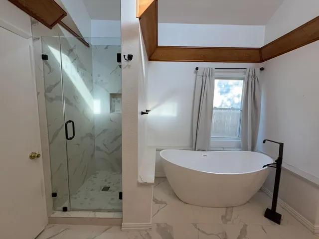 an empty room with a window and chandelier fan