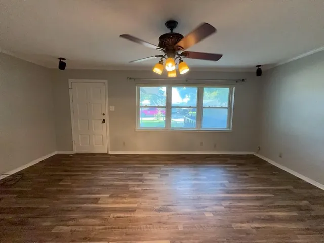 a view of an empty room with window and wooden floor