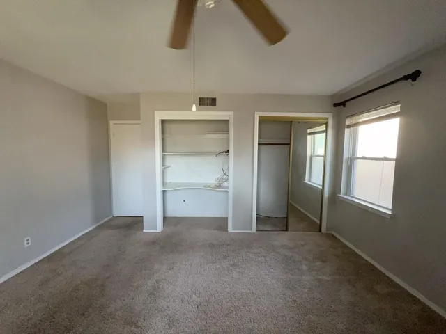 a view of an empty room with window and cabinet area