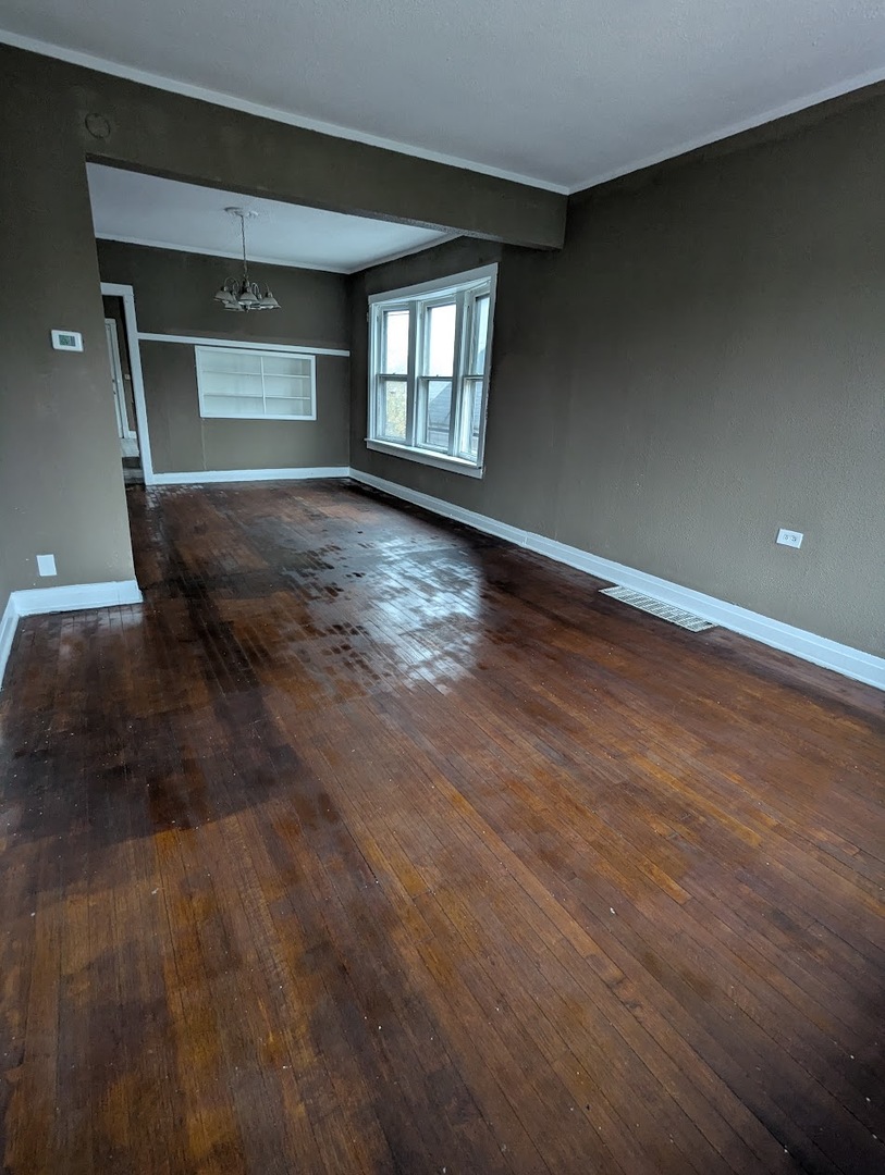 324 West 112th Street Chicago, IL 60628 - Photo 3 of 17 an empty room with wooden floor and windows