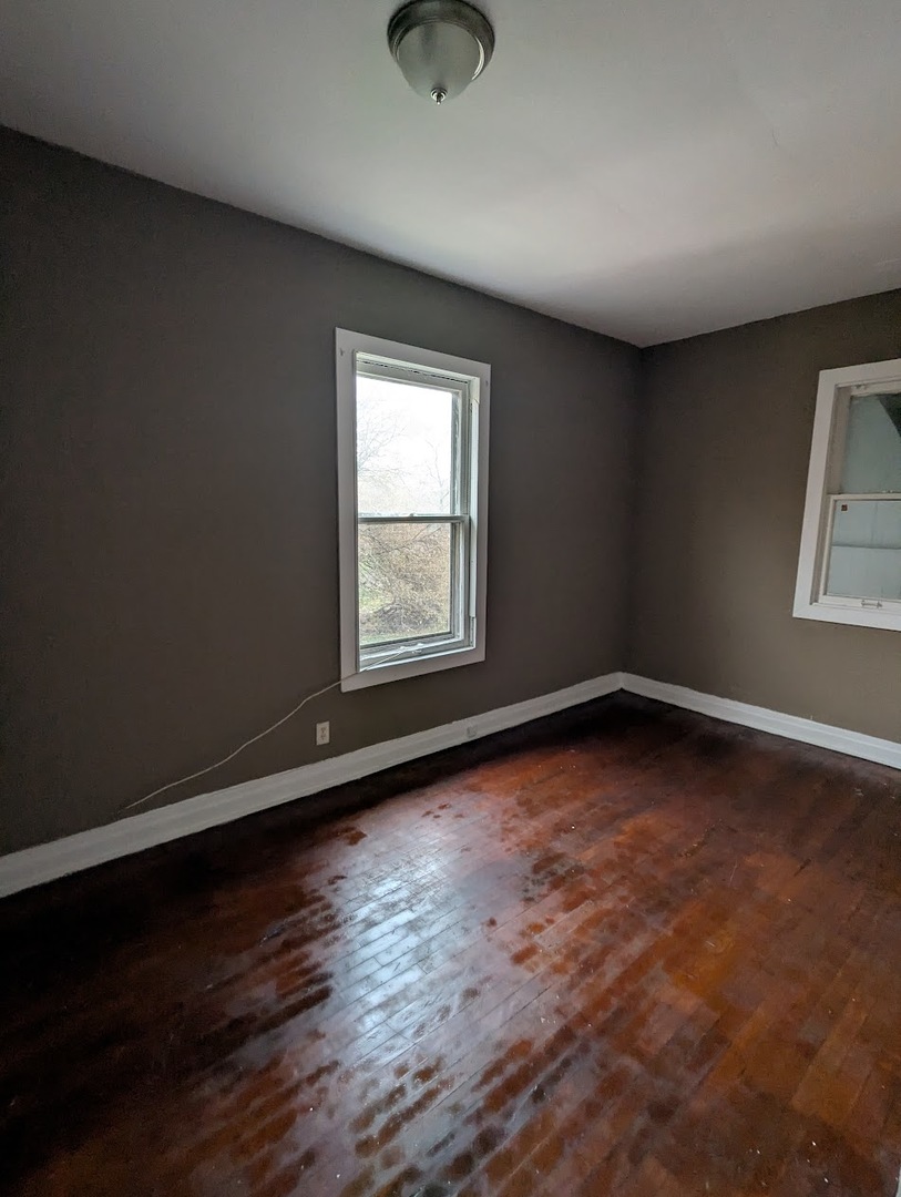 324 West 112th Street Chicago, IL 60628 - Photo 10 of 17 an empty room with wooden floor and windows