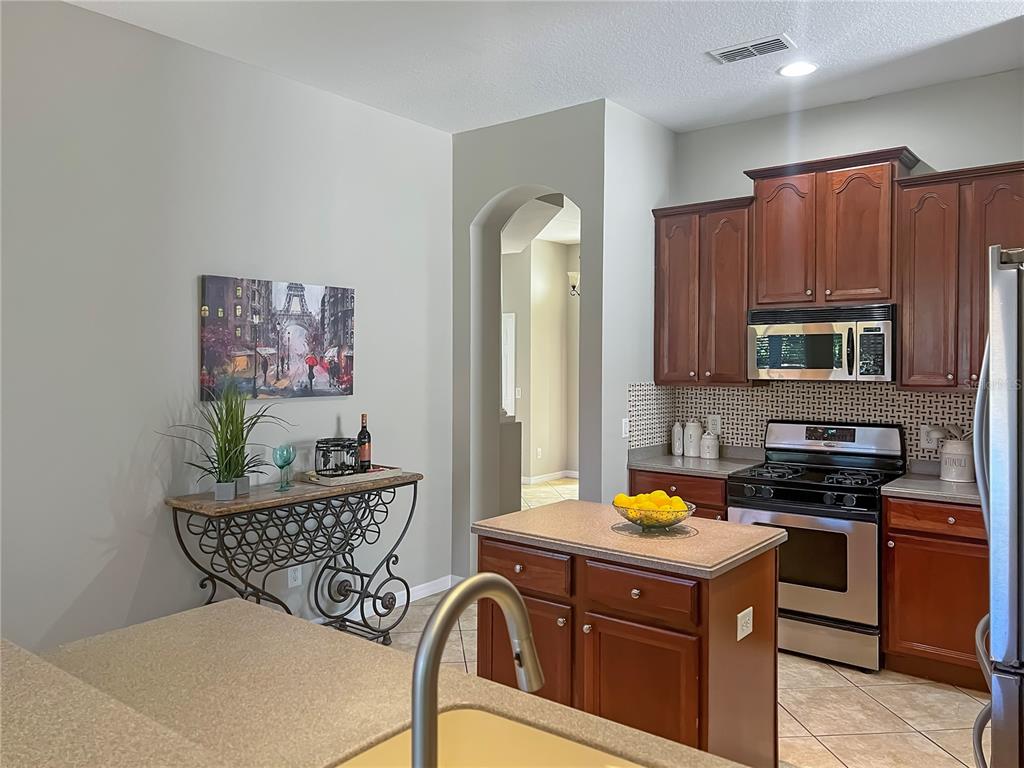 11531 Vicolo Loop Windermere, FL 34786 - Photo 6 of 32 a kitchen with stainless steel appliances granite countertop a stove top oven a sink a dining table and chairs