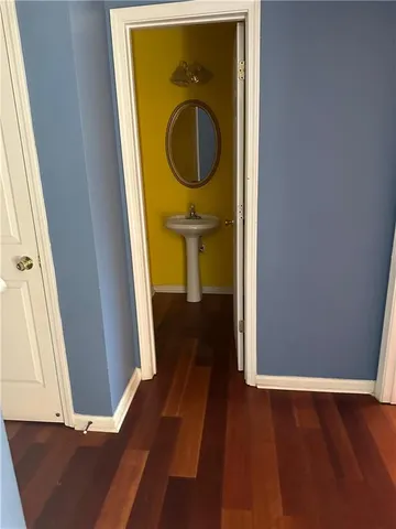 a view of a hallway with wooden floor and a bathroom