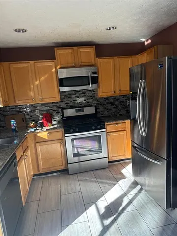 a kitchen with granite countertop a refrigerator and a stove top oven