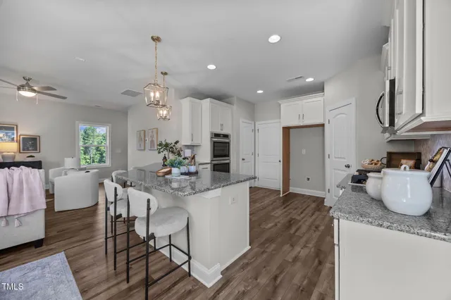 a kitchen with kitchen island granite countertop a sink cabinets and wooden floor