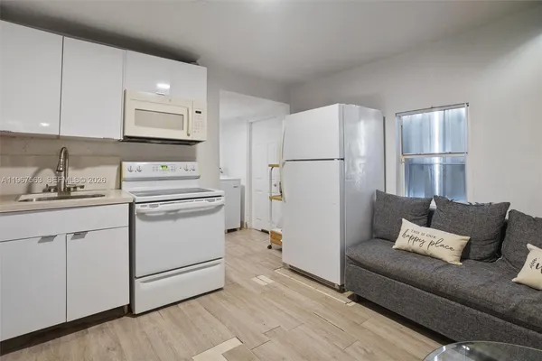 a living room with white cabinets and white appliances