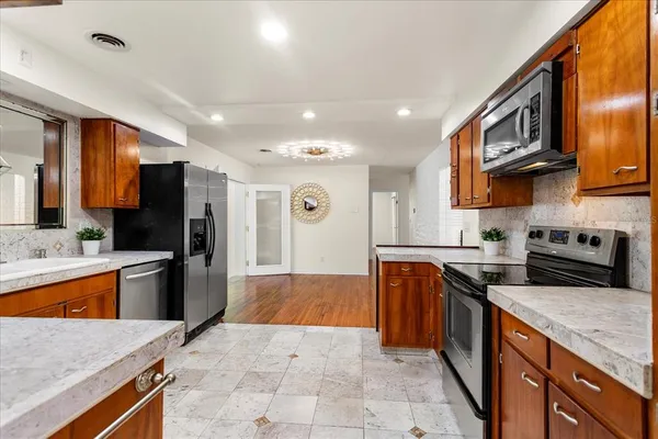 a large kitchen with stainless steel appliances granite countertop a stove refrigerator a sink dishwasher and wooden cabinets with wooden floor