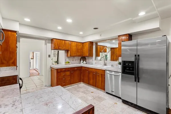 a large kitchen with stainless steel appliances granite countertop a refrigerator and a sink