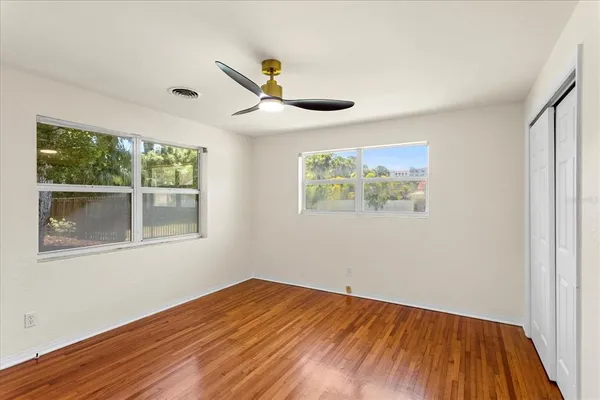 a view of an empty room with wooden floor and a window