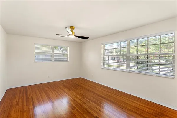 a view of empty room with wooden floor and fan