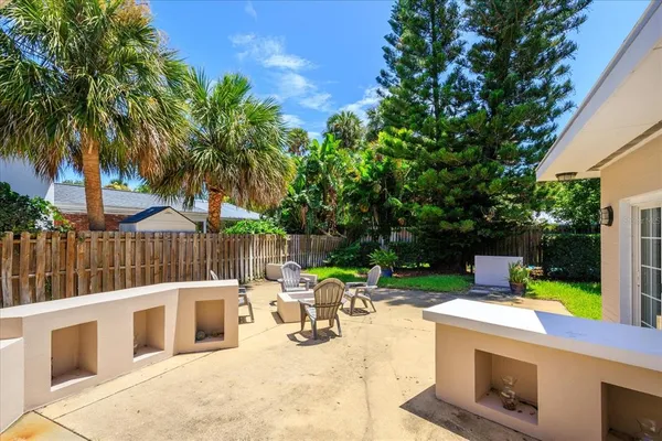 a view of a patio with a table and chairs under an umbrella with palm trees